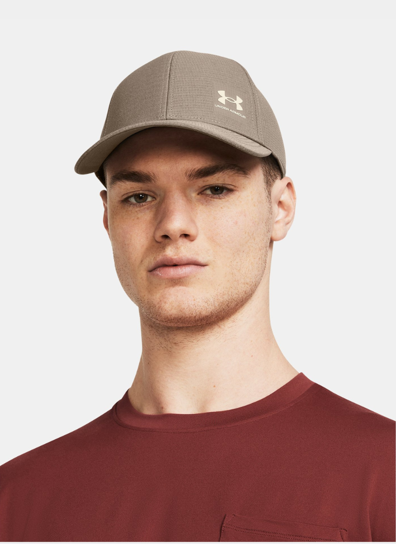 Person wearing a Beige cap with Under Armour logo on a white background