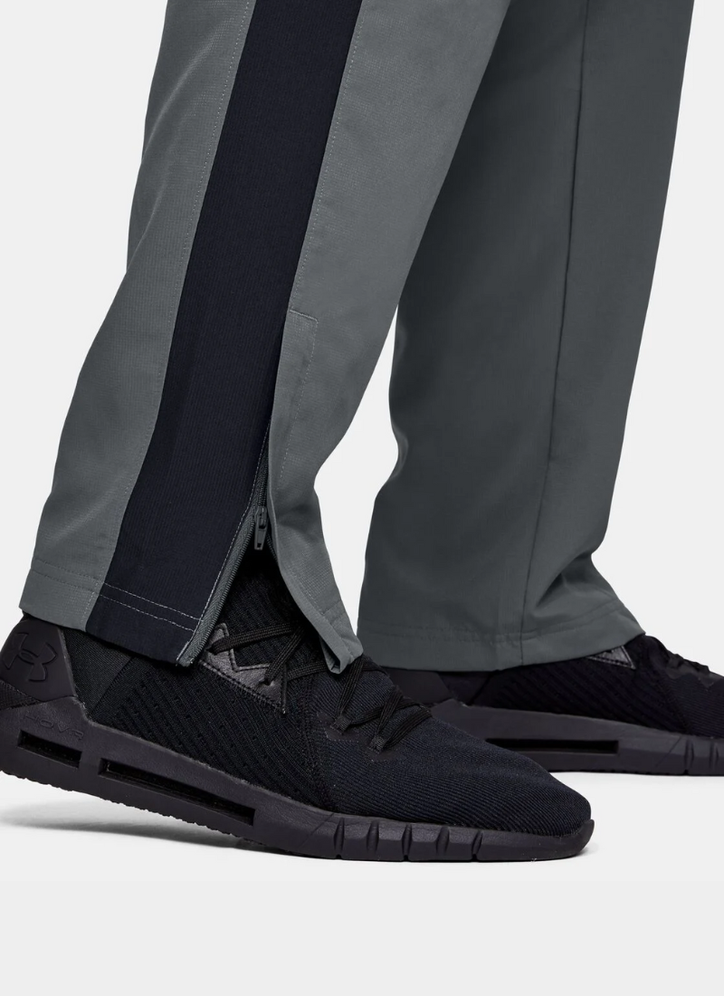 Close-up of black athletic shoes and gray pants on a light gray background