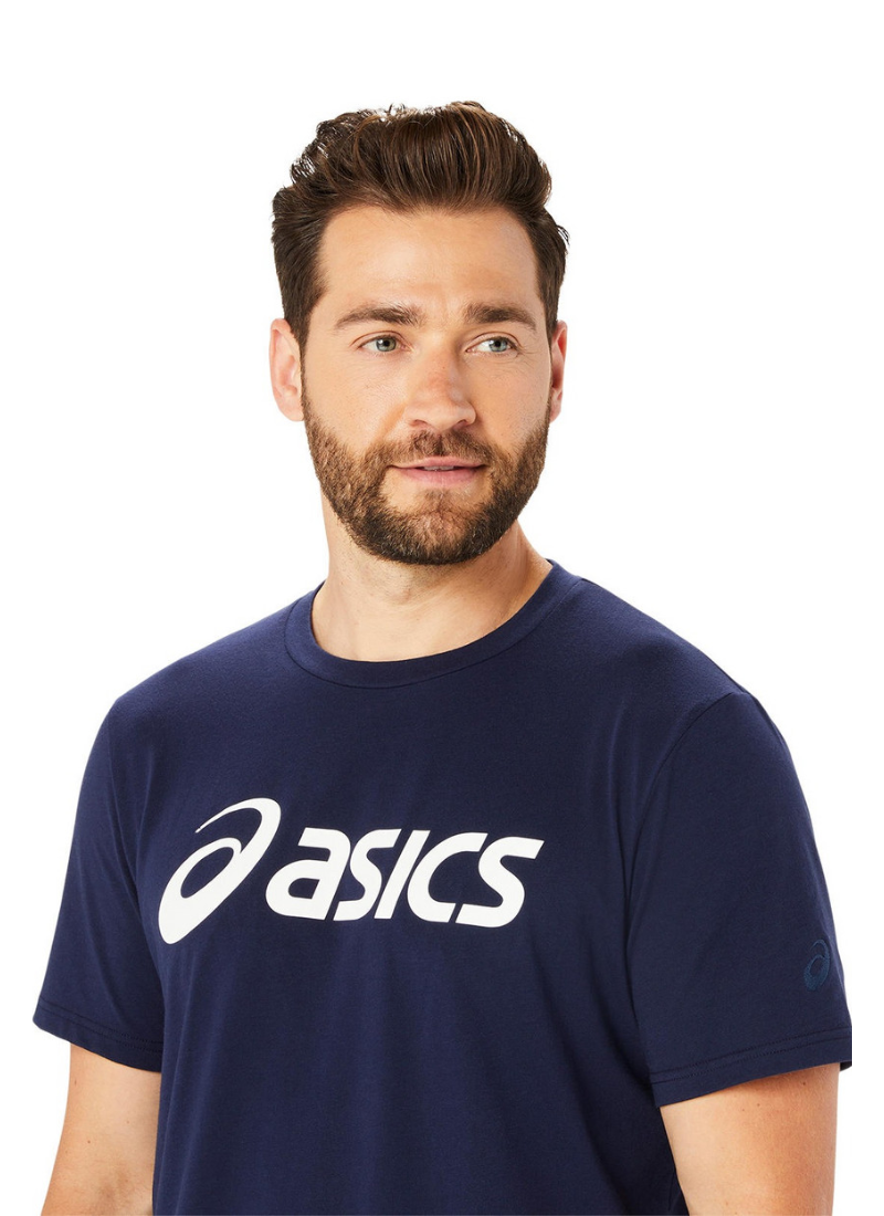 Man wearing a navy blue Asics t-shirt on a white background, tight shot