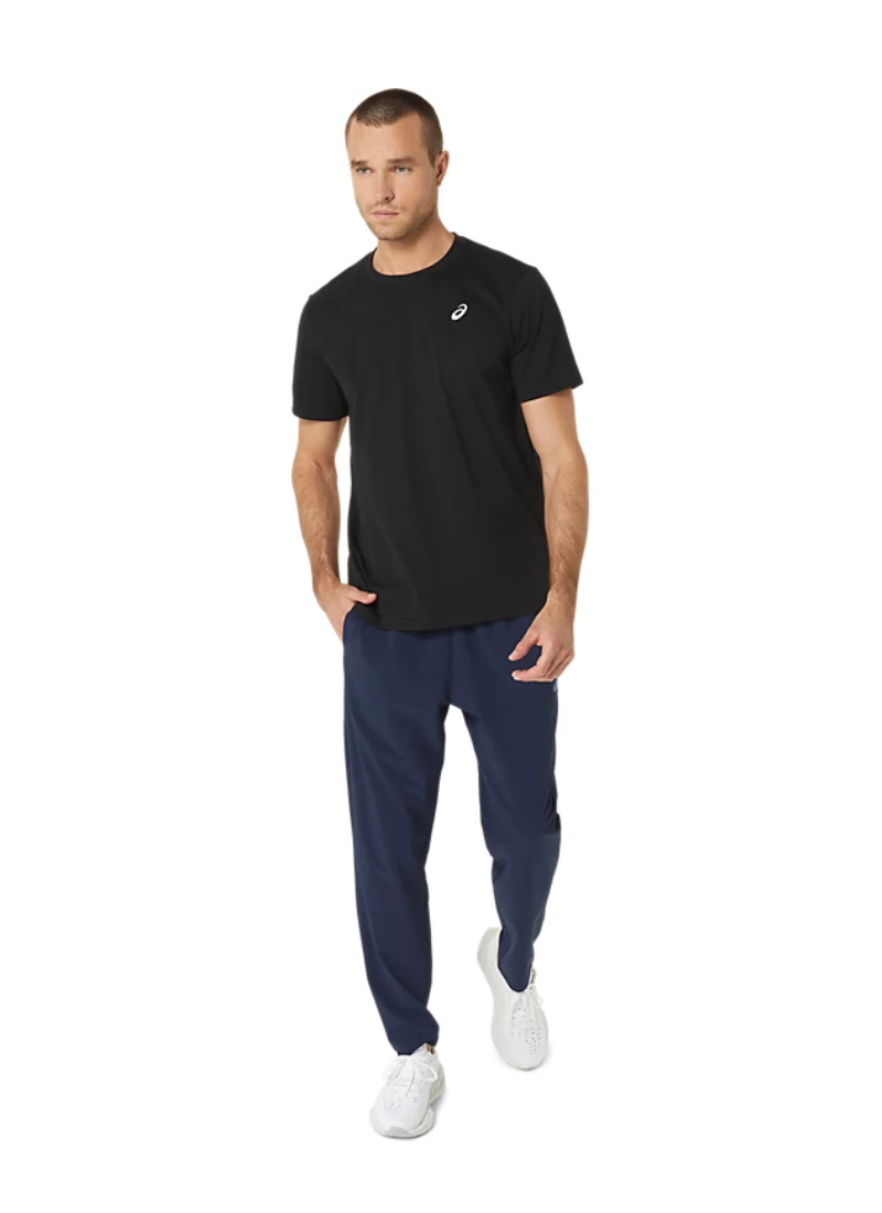 Man wearing a black t-shirt with an Asics white logo and blue pants on a white background, full view