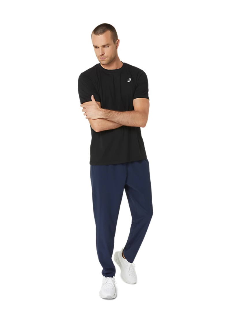 Man wearing a black t-shirt with a white Asics logo on a white background, full shot
