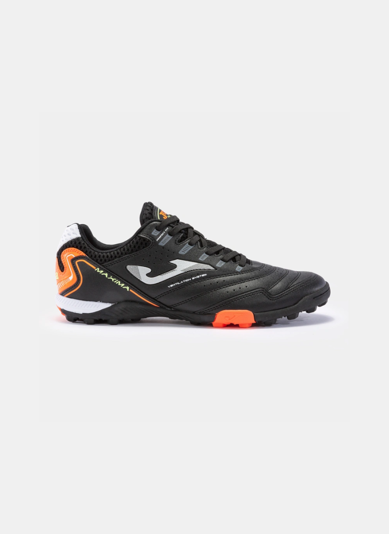 Outer side profile view of the Joma Maxima 2301 turf shoe showing the black synthetic body, silver Joma emblem, orange heel accents, and orange forefoot outsole wrap.
