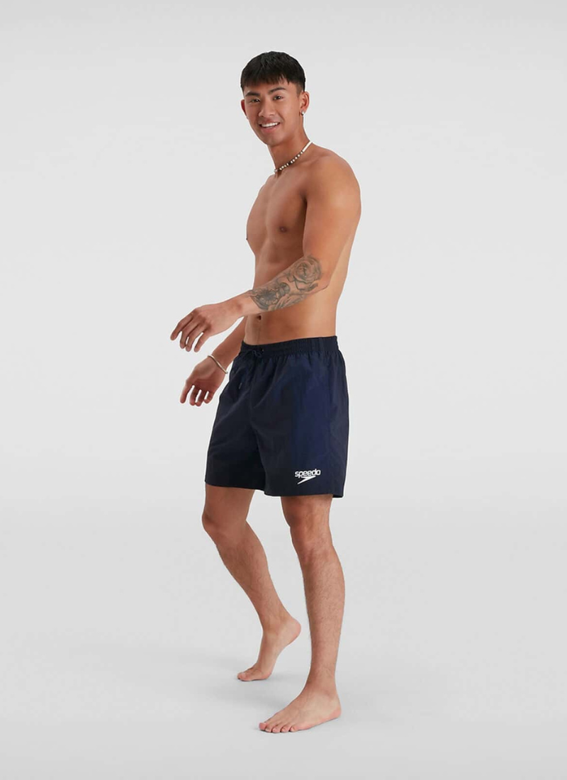 Man wearing navy swim shorts with a brand logo on a white background