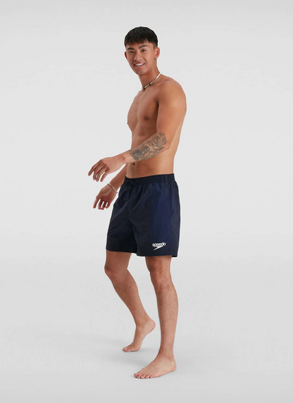 Man wearing navy swim shorts with a brand logo on a white background