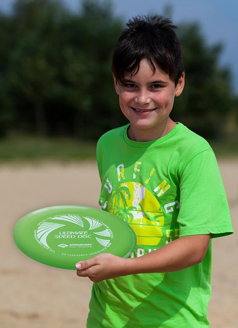 Boy holding a green Schildkröt Ultimate Speed Disc frisbee on a sandy beach